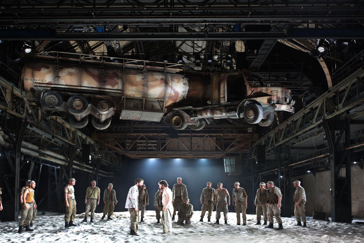 Menschen auf der Bühne bei Ruhrtriennale in der Jahrhunderthalle Bochum, von der Decke hängt ein LKW